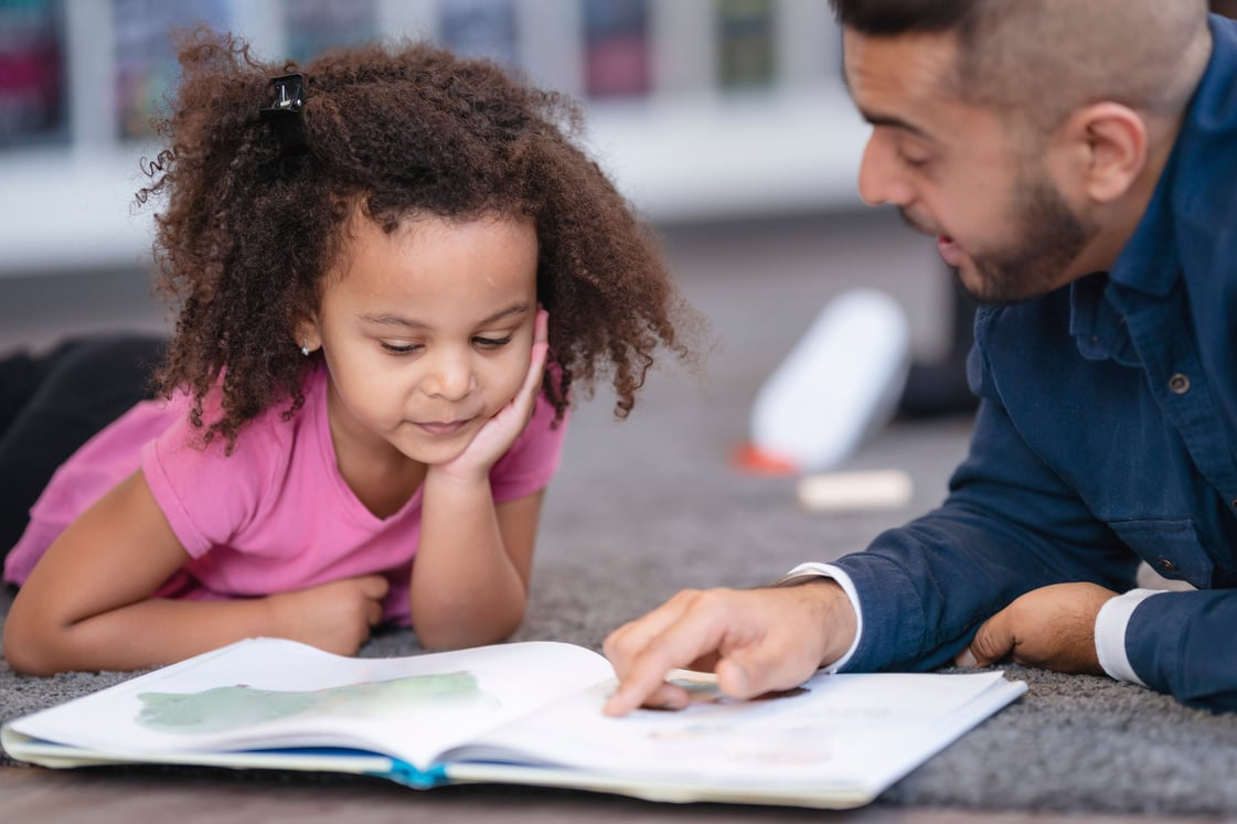 Kindergarten teacher reading book to student